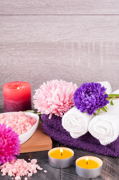 Spa background. Sea salt, towel, scented candle and flowers for