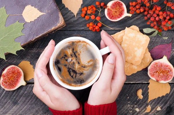 Female hands holding cup of coffee on wooden background. Old boo