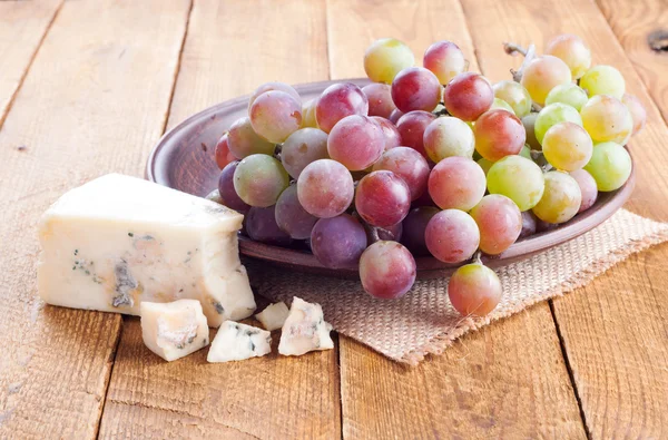 Grapes and blue cheese on wooden background. Tasty snacks