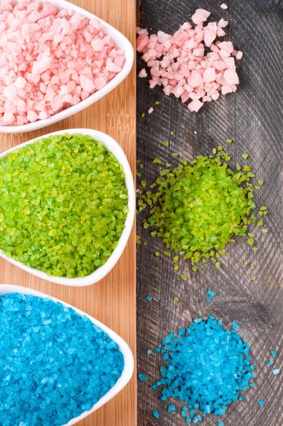 Blue, green and pink sea salt for spa treatments on old wooden b