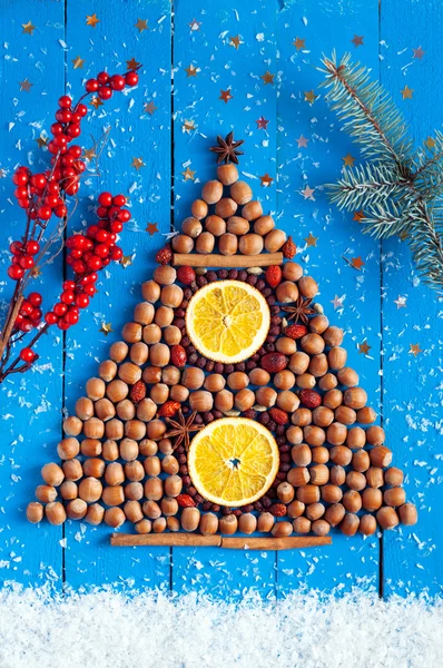Christmas background. Christmas tree shaped nuts, berries and sp