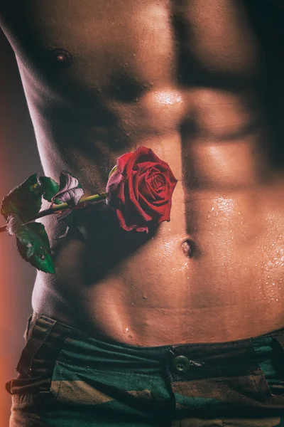 Muscular shirtless macho man with rose