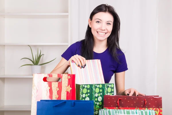 Smiling happy girl prepares bags gifts for Christmas