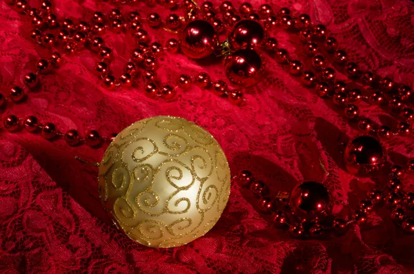 Christmas Decorations On A Red Background Accessories. Gold Ball Toy With Bright Lace.