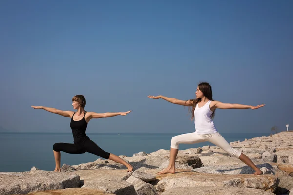 Women practicing yoga on the beach