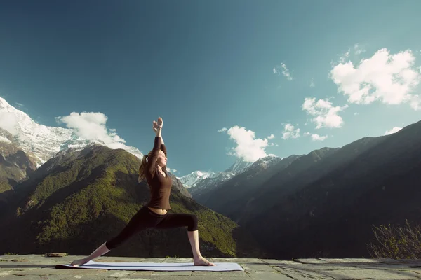 Woman in mountains doing yoga exercises