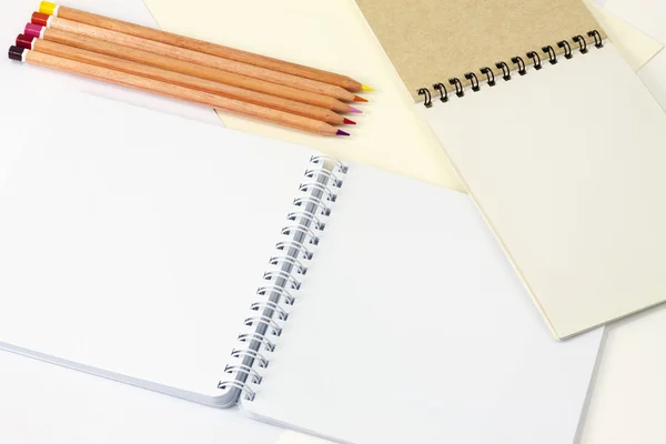 Two notepad with different type of paper and colored pencils.