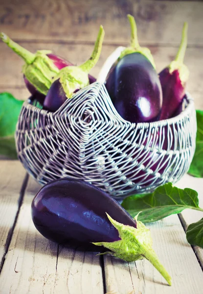 Organic Eggplants and Basket on the wooden background, still life