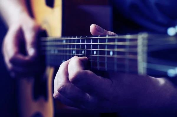 Hands playing acoustic guitar