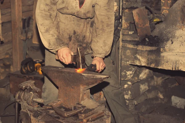 Detail shot of hammer forging hot iron at anvil