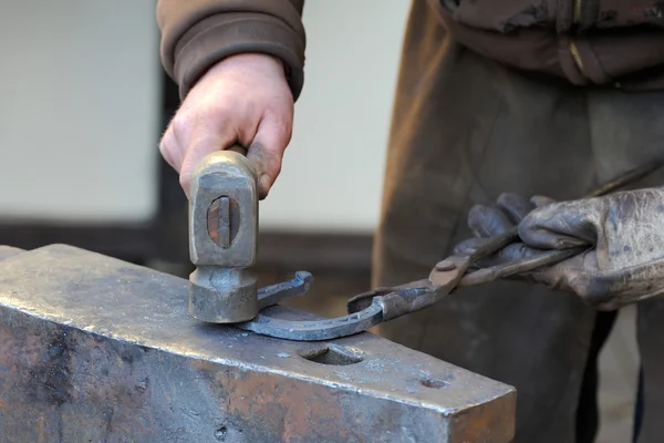 Blacksmith forges a horseshoe