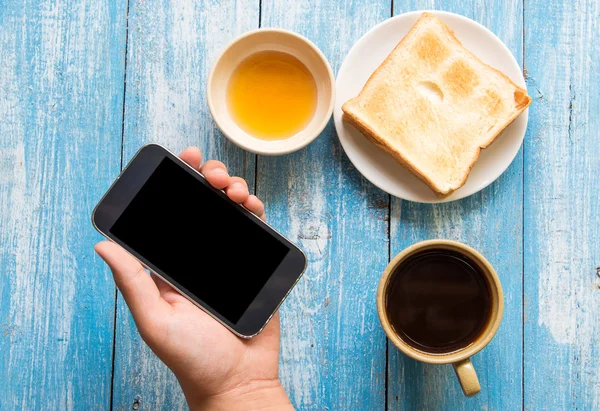 Black display Smart phone in hand , Toast , Honey , Coffee cup o