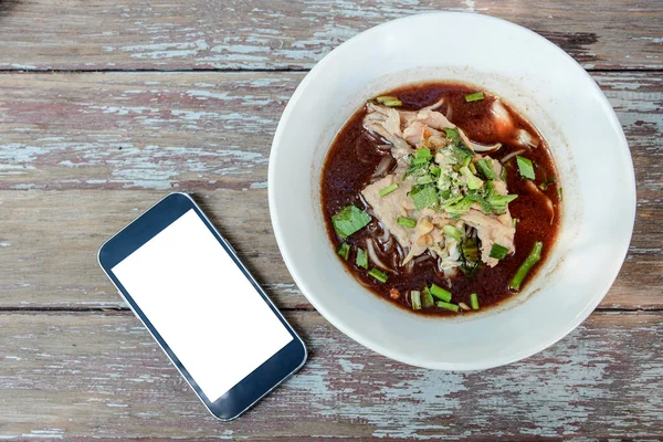 Thai noodle in white Bowl , White display Smart phone beside bow