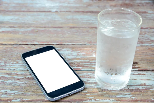 White display Smart phone on wooden table , glass of water on si
