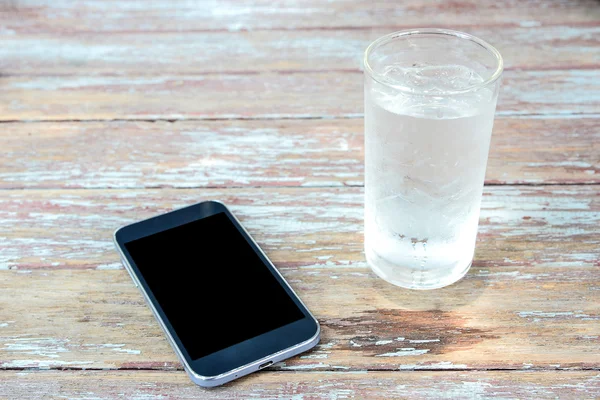 Black display Smart phone on wooden table , glass of water on si