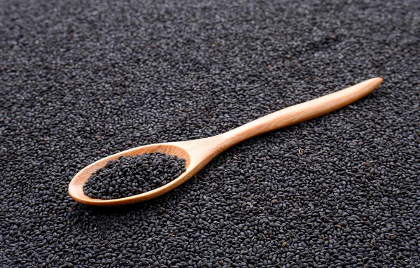 Black sesame  in wooden spoon on sesame background.