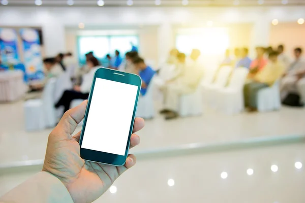 White display smart phone in hand on blur people meeting backgro