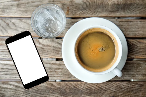 White coffee cup and glass water with smart phone on wooden tabl