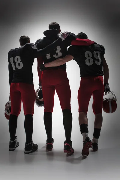 The three american football players on gray background
