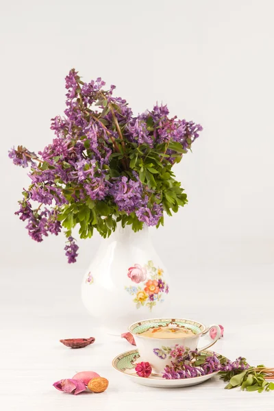 Tea with  lemon and bouquet of  lilac primroses on the table