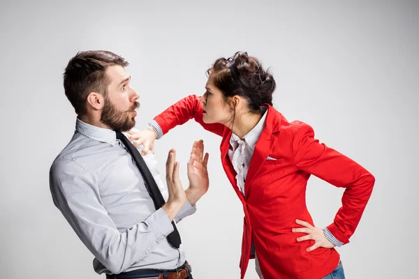 The angry business man and woman conflicting on a gray background