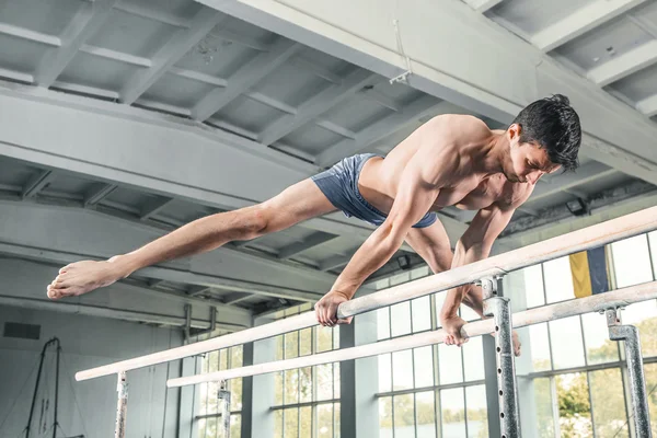 Male gymnast performing handstand on parallel bars