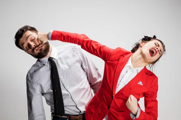 The angry business man and woman conflicting on a gray background