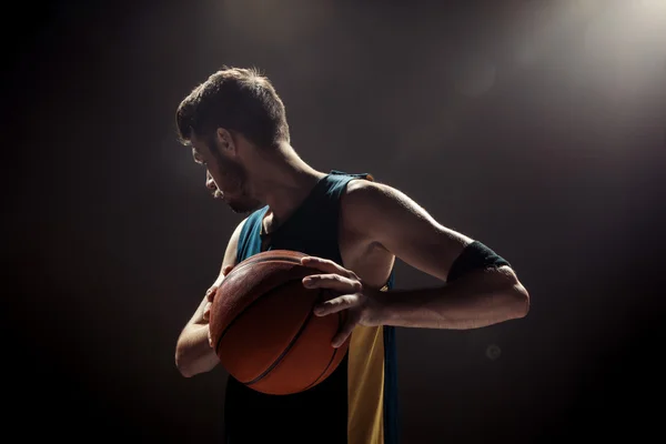 Silhouette view of a basketball player holding basket ball on black background