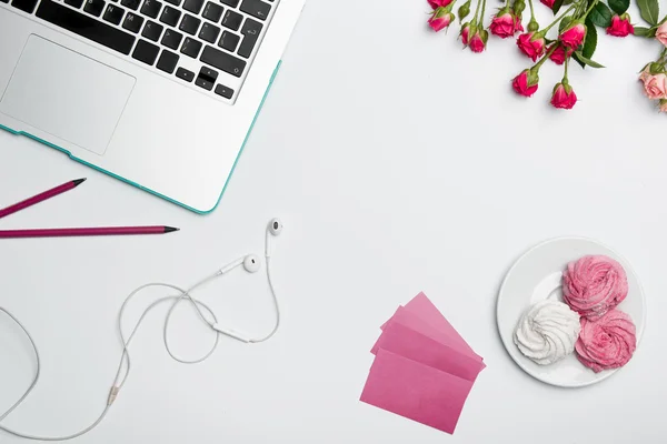 Office desk table with computer, supplies, flowers