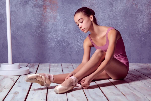 Young ballerina putting on her ballet shoes.