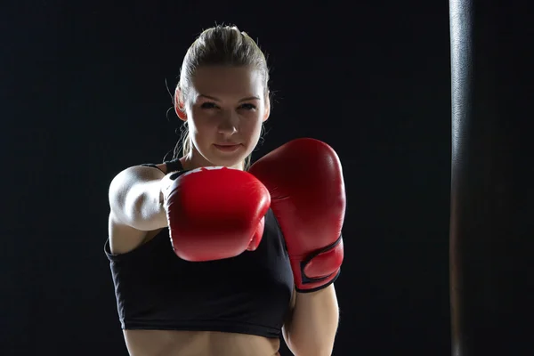 Beautiful woman is boxing on black background