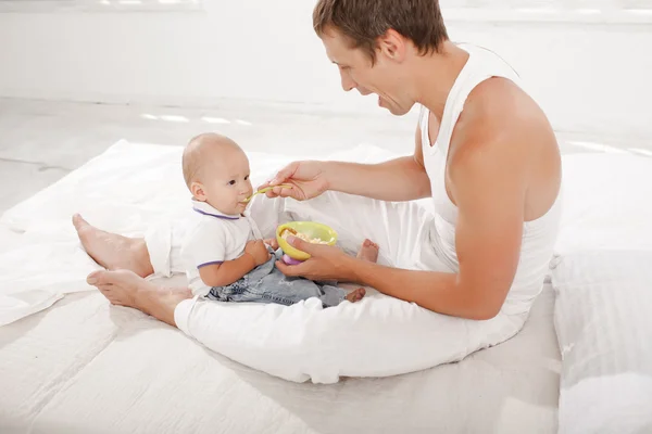 Young father with his nine months old son on the bed at home