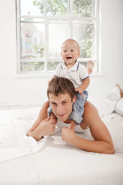 Young father with his nine months old son on the bed at home