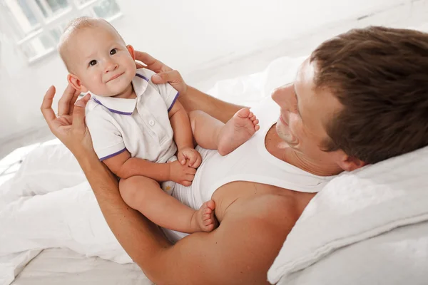 Young father with his nine months old son on the bed at home