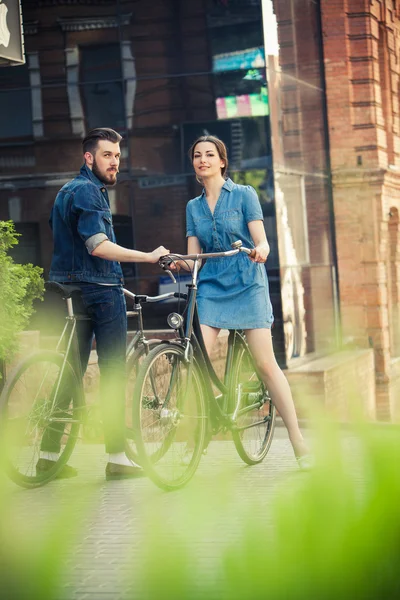 Young couple sitting on a bicycle opposite the city