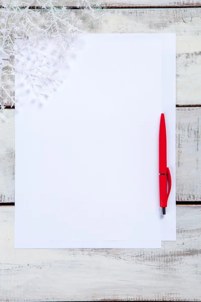The blank sheet of paper on the wooden table with a pen