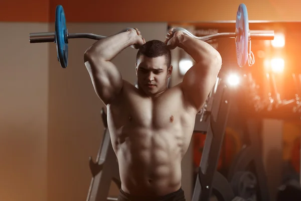 Fitness man exercising with barbell in gym