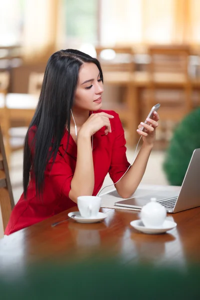 Young woman with phone and laptop sitting in the cafe