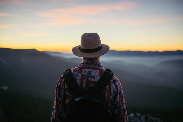 Man in hat with bag looking at the sunset