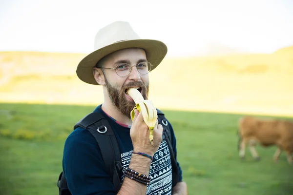 Hipster man eating a banana