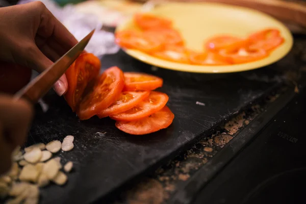 Close-up of a female hand cutting a tomato