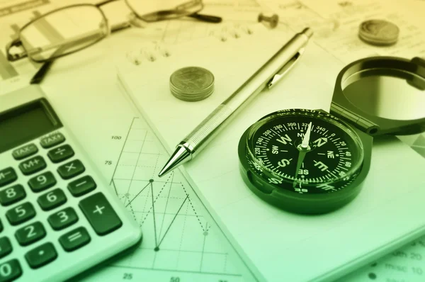 Compass, pen, glasses and coin on notebook, accounting backgroun