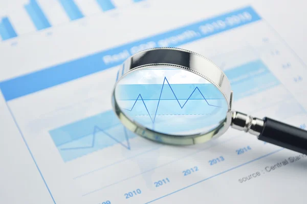 Magnifying glass over financial chart and graph business