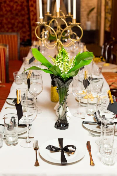 Birthday guests table setting with fresh flowers in black and gold style, indoor