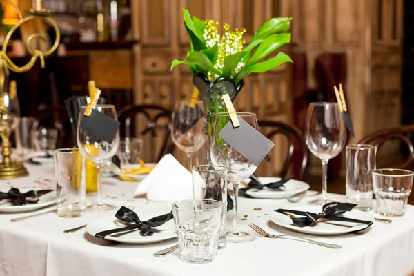 Birthday guests table setting with fresh flowers in black and gold style, indoor