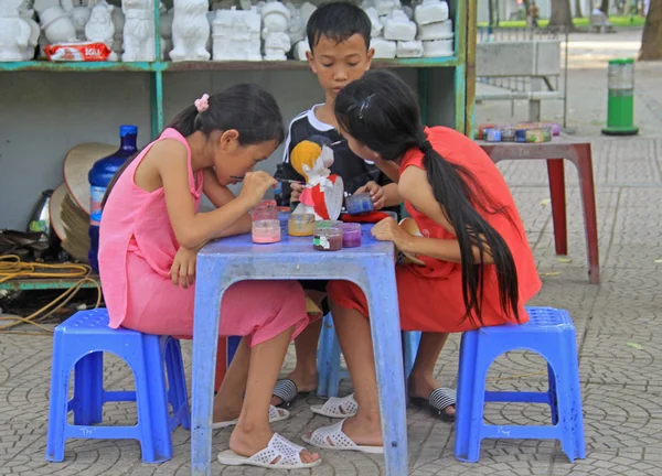 Kids are painting doll on the street in Hanoi, Vietnam