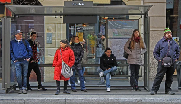 People are waiting for bus on stop station in Milan