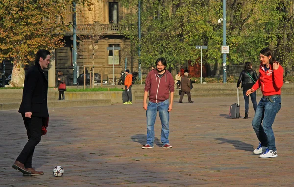 Three guys are playing football in park of Milan