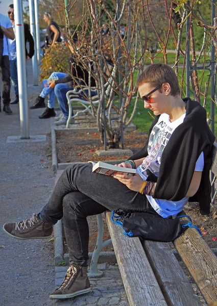 Guy is reading a book at the bench in Graz, Austria
