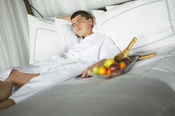 Gorgeous young man (gentleman) lying on a bed at the hotel.